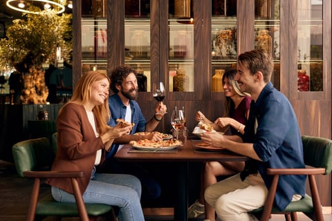 Group of friends sharing laughter, wine, and a meal in a modern setting