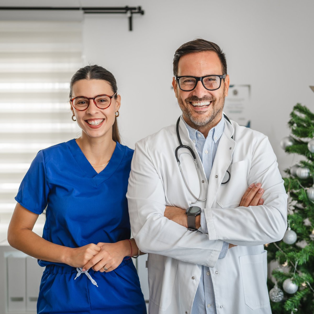 Doctor and nurse standing together, smiling warmly in a healthcare setting
